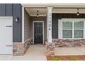 Inviting front entry with stylish stone accents, pendant lights, and a modern black door at 11204 Cornerstone Way, Hampton, GA 30228
