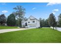 Wide shot of a beautiful white home surrounded by a lush green lawn and trees, creating a serene atmosphere at 136 Huntcliff Trl, Ellenwood, GA 30294