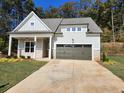 Charming single-Gathering home featuring light gray siding, white trim, a covered porch, and an attached two-car garage at 3032 Farm Tract Trl, Woodstock, GA 30189