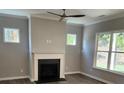 Cozy living room featuring a fireplace, hardwood floors, large windows overlooking the backyard, and neutral paint at 3032 Farm Tract Trl, Woodstock, GA 30189