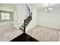 Bright living room featuring neutral carpet, a modern chandelier, and staircase at 4417 Belcamp Rd, Fairburn, GA 30213