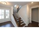 A well-lit foyer features gleaming hardwood floors, staircase with elegant banister, and a double glass door at 574 Sawnee Village Blvd, Cumming, GA 30040