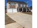 Two-story home featuring a two-car garage, brick facade, and a covered front porch with stately columns at 1367 Midnight Ride Ct, Hampton, GA 30228