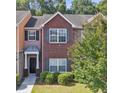 Attractive townhome featuring brick accents, manicured bushes, and lush green lawn at 2612 Haligan Pointe, Riverdale, GA 30296