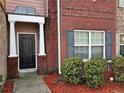 A close-up of a brick townhome entrance with a black door and manicured shrubbery at 2612 Halligan Pointe, Riverdale, GA 30296