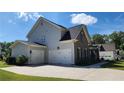 Charming home featuring a two-car garage, neutral siding, and partial brick exterior under a clear blue sky at 2903 Eva Clb, Acworth, GA 30101