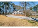 A long driveway leads to a gray two-story home nestled among tall trees, showcasing its expansive lot at 3777 Clubhouse Way, Conyers, GA 30094