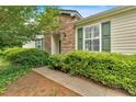 A view of home's stone facade, trimmed lawn, and green shrubs along sidewalk at 627 W Oaks Dr, Woodstock, GA 30188