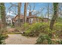 A charming brick home sits nestled in a lush backyard with mature trees and inviting gravel path at 698 Bellemeade Nw Ave, Atlanta, GA 30318