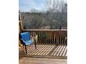 Back deck with dark wooden flooring, a blue metal chair, and a wooden railing overlooking the trees at 201 Balaban Cir, Woodstock, GA 30188