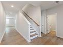 Bright hallway featuring wood-look flooring, a staircase with a wood handrail, and white walls at 4155 Viola Pl, Atlanta, GA 30349