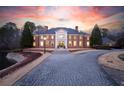 Stately brick mansion with manicured landscaping, long paved driveway, and grand entrance at sunset at 4615 Northside Dr, Atlanta, GA 30327