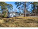 White home with a carport is set among mature trees on a lush, grassy lot at 1890 Carla Dr, Morrow, GA 30260