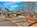 Property view showing home, two-car garage, additional building, and expansive driveway at 360 Chimney Ct, Fairburn, GA 30213