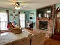 Cozy living room featuring a brick fireplace, plush seating, and ample natural light from the windows at 1536 Hunters Cv, Auburn, GA 30011