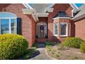 Close-up of the brick home's entrance, showcasing the door, wreath, and manicured landscaping at 811 Weeping Willow Dr, Powder Springs, GA 30127