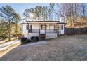 Charming home features a covered front porch, dark trim, manicured bushes, and a cozy curb appeal at 2571 Hamill Dr, Buford, GA 30519