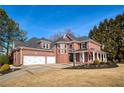 Spacious brick home boasts a three-car garage, columned front porch, and lush landscaping at 1605 Ridge Haven Run, Alpharetta, GA 30022