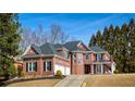 Large brick home with three-car garage, manicured lawn, mature trees, and well-maintained landscaping at 1605 Ridge Haven Run, Alpharetta, GA 30022