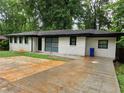 Ranch style home with freshly poured concrete driveway and white painted brick, surrounded by mature trees at 3490 Primrose Pl, Decatur, GA 30032