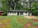 Ranch style home with white painted brick and dark trim, surrounded by mature trees at 3490 Primrose Pl, Decatur, GA 30032