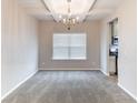 Bright dining room featuring neutral walls, carpeted floor, and modern chandelier at 7434 Rudder Cir, Fairburn, GA 30213
