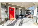 Inviting front porch with a bright red door, potted plants, bench, and swing offering a cozy outdoor space at 2599 Church Nw St, Atlanta, GA 30318