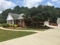 View of the home with a red brick exterior, lush green lawn, and a long driveway at 3220 Indian Shoals Rd, Dacula, GA 30019