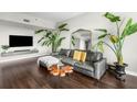 Bright living room featuring a gray leather sofa, hardwood floors, and large plants for a modern aesthetic at 565 Peachtree St # 1311, Atlanta, GA 30308