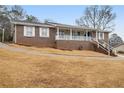 Charming brick home features a covered front porch, white railings, and a well-maintained yard at 6069 Shallow Wood Ln, Douglasville, GA 30135
