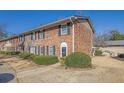 Two-story brick townhome featuring manicured shrubs, dark shutters, and a concrete walkway at 413 Northdale Ct, Lawrenceville, GA 30046