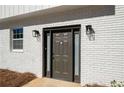 Front door featuring a dark-painted wood door, sidelights, modern sconces, and light-painted brick facade at 3001 W Potomac Dr, Atlanta, GA 30344