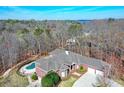 Aerial view of the brick home, surrounded by lush trees and a sparkling pool at 5040 Blackberry Ln, Buford, GA 30518