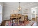 Elegant dining room with wainscoting, modern chandelier, and view into kitchen area at 1835 Berkeley Ne Mews, Atlanta, GA 30329