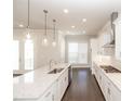 Bright kitchen features white cabinets, granite countertops, stainless steel appliances and modern pendant lighting at 167 Basil Street, Cumming, GA 30040