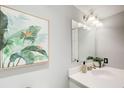 Stylish half-bathroom featuring a white sink, framed tropical artwork, modern light fixtures, and elegant, neutral tones at 3721 Stonewall Se Cir, Atlanta, GA 30339