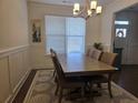 Bright dining room with a modern chandelier, wainscoting detail, and a large window for natural light at 1200 Bar Harbor Pl, Lawrenceville, GA 30044