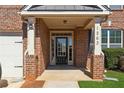 Close-up of the front door entry featuring brick columns, white trim, and glass pane door at 1263 Polk Xing, Mcdonough, GA 30252