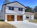 Beautifully renovated two-story home with white brick, black trim, wood garage doors, and a stylish arched entry at 406 Jordan Dr, Tucker, GA 30084