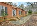Close up view of a brick home with a curved brick staircase leading to the front door and surrounding landscaping at 105 Spring Forest Way, Sharpsburg, GA 30277