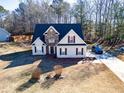An elevated view of a two-story home with stone facade, a long driveway, and a well-manicured front yard at 205 Trelawney Place, Covington, GA 30016