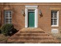 Close-up of a brick home's entry, with a green front door, brick steps, and sconces at 270 Grapevine Run, Sandy Springs, GA 30350