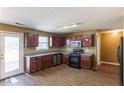 A cozy kitchen with dark wood cabinets, laminate counter tops, and a gas range at 7635 Jumpers Trl, Fairburn, GA 30213