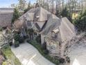 An aerial view shows this stately home's stone and brick facade, mature trees, and curved driveway at 3871 Trickum Road Ne, Marietta, GA 30066