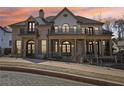 Elegant brick home with a charming front yard, second story terraces, and manicured landscaping at dusk at 440 Belada Blvd, Sandy Springs, GA 30342