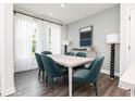 This dining room features six plush blue chairs around a white table and large windows covered with elegant white curtains at 345 Skylar Se Way, Atlanta, GA 30315