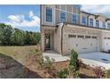 Charming townhome exterior with a brick facade, two-car garage, and manicured lawn on a sunny day at 579 Collections Dr, Lawrenceville, GA 30043