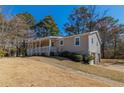 View of ranch style home with a side entry garage, covered front porch, and mature landscaping at 5498 Balmoral Dr, Douglasville, GA 30135