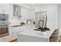 Modern kitchen featuring stainless steel appliances, an island with chairs, and sleek white cabinets at 2425 Peachtree Ne Rd # 903, Atlanta, GA 30305