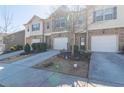 A row of townhomes featuring brick and neutral siding, each with a single-car garage and landscaping at 3293 Pennington Dr, Stonecrest, GA 30038